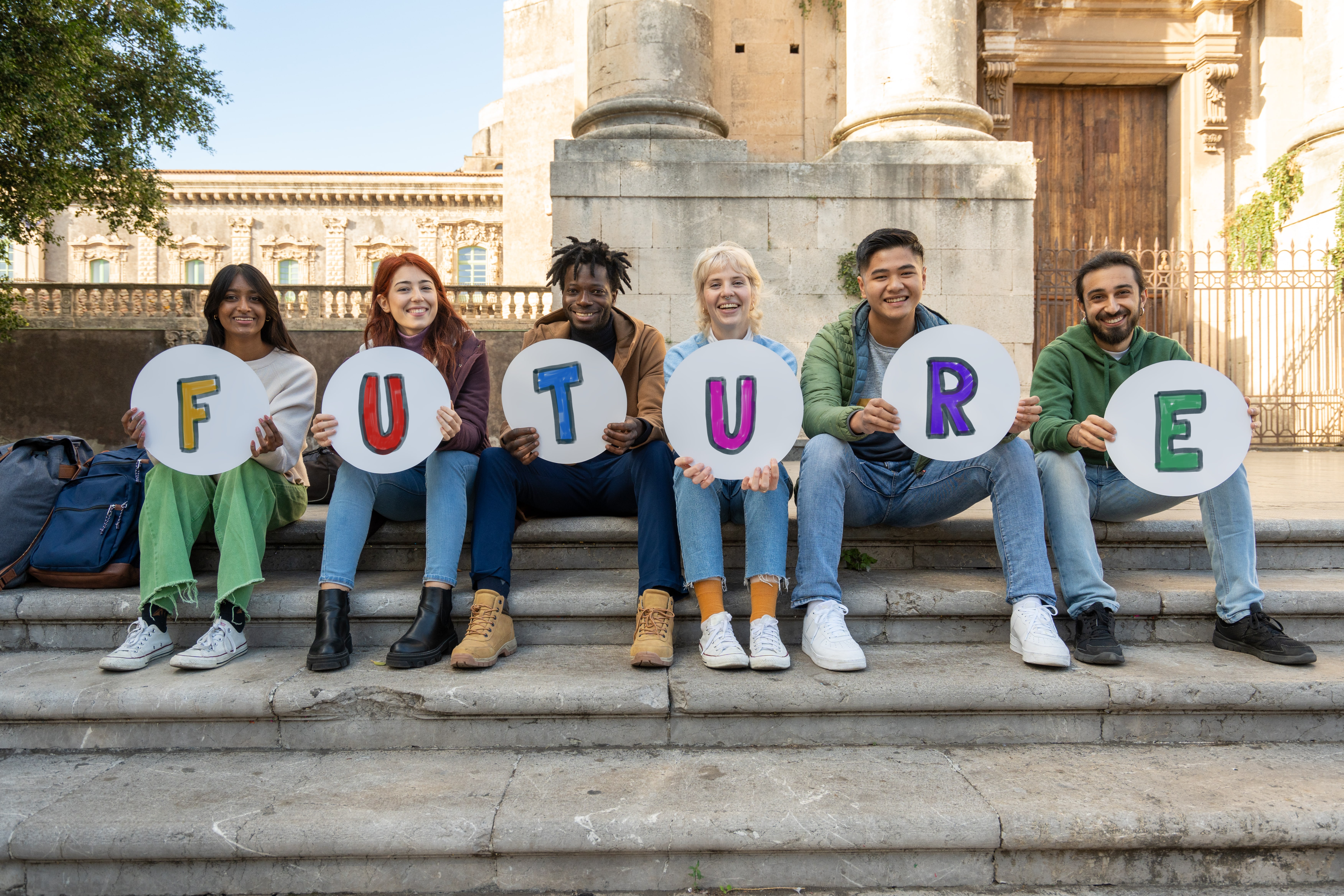 Cheerful diverse group of students holding handwritten 'FUTURE' signs on university campus. Multicultural young people representing hope, education, and diversity. Concept of next generation, aspirations, and inclusive higher education.